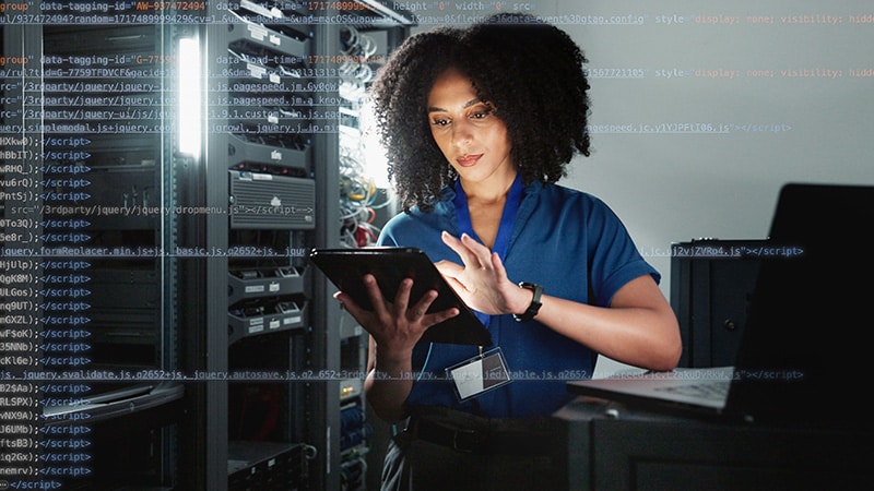 A woman wearing a blue shirt is holding a tablet, appearing attentive as she interacts with the device.